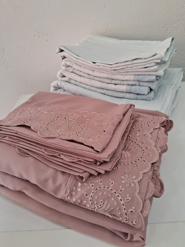 Enxoval de cama dobrado com perfeição em tons rosa e branco